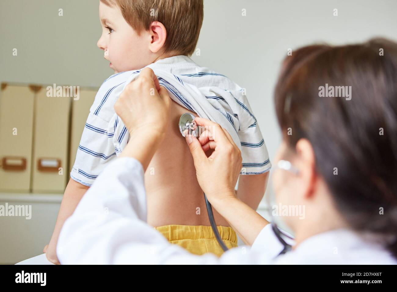 Pediatrician listening to a child's lungs on the back with a