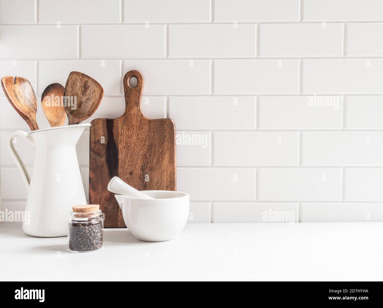 Stylish white kitchen background with kitchen utensils standing on white  countertop, empty space for text, front view Stock Photo - Alamy