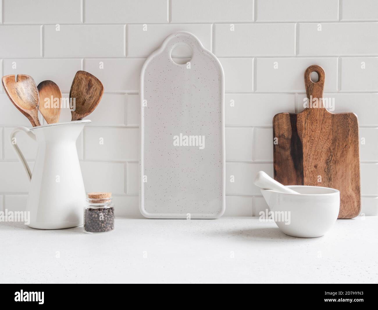 Stylish white kitchen background with kitchen utensils and whie ceramic board for text on white countertop, copy space, front view Stock Photo