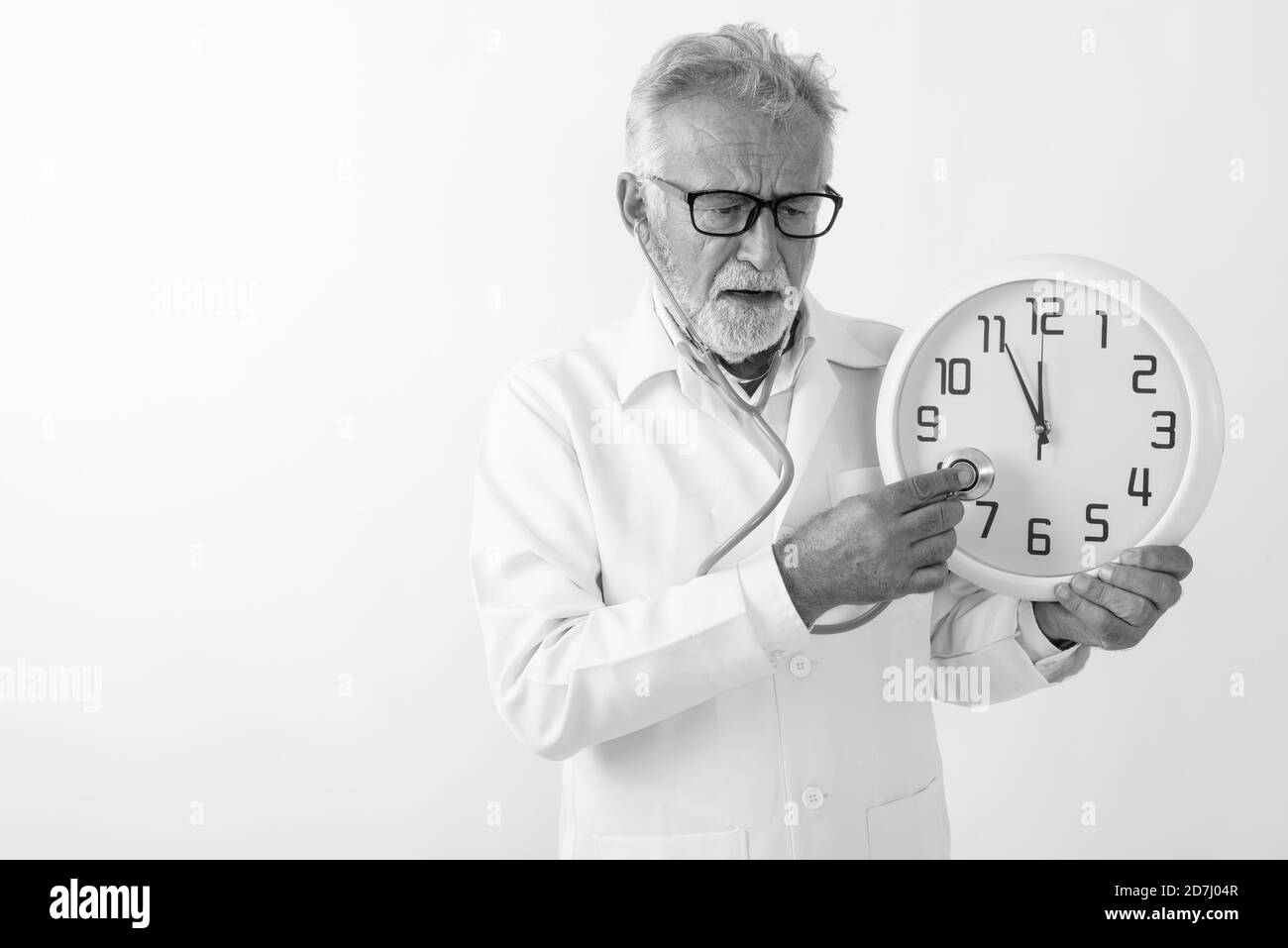 Studio shot of handsome senior bearded man doctor using stethoscope on wall clock against white background Stock Photo
