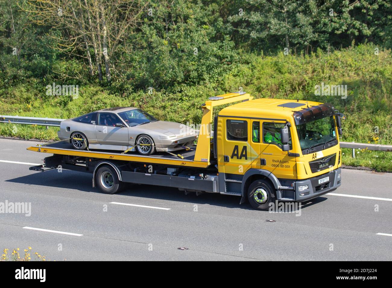 Partially restored Triumph TR7 classic car on AA car transporter. Roadside breakdown recovery;  Haulage delivery trucks, lorry, transportation, truck, vehicle delivery recoveries, commercial transport industry, on the M6 at Manchester, UK Stock Photo