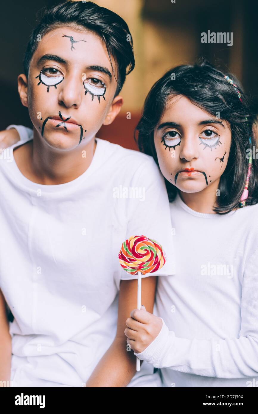 Brother and sister with Halloween face paint, holding lollipop Stock Photo  - Alamy