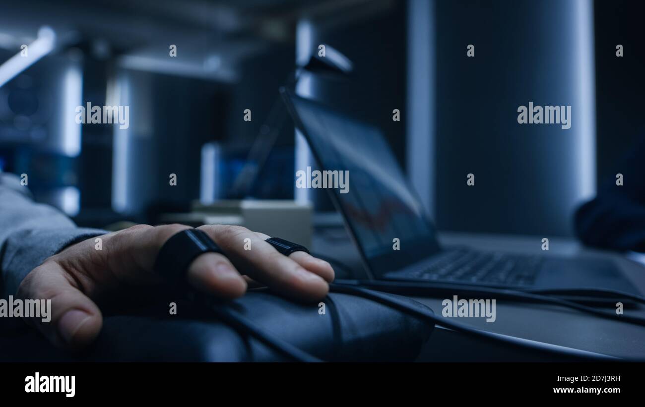 Close-up Shot of the Suspect's Hand Connected to the Lie Detector Polygraph Test Machine, while Female Special Agent Conducts Questioning.  Stock Photo