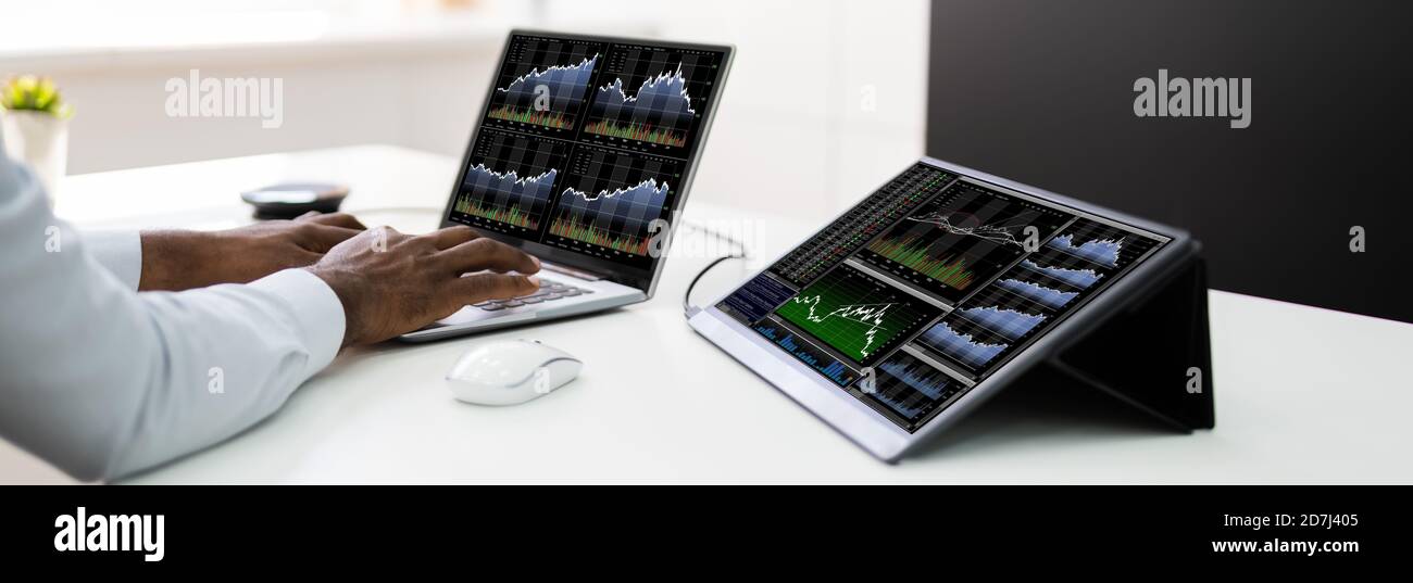 Stock Exchange Analyst Using Multiple Laptop Computer Screens Stock Photo