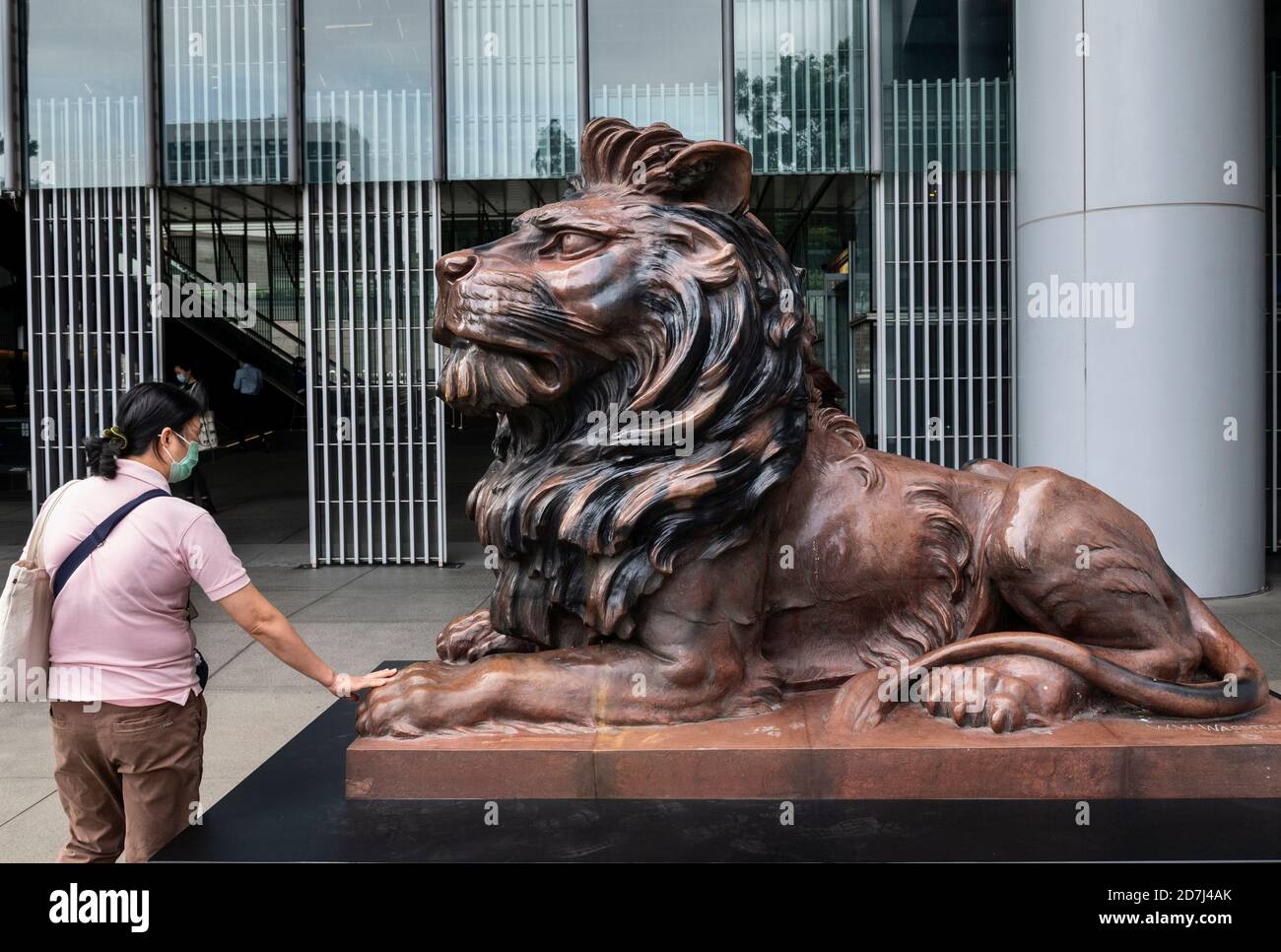 A woman touches the paws of a bronze lion statue, restored after pro
