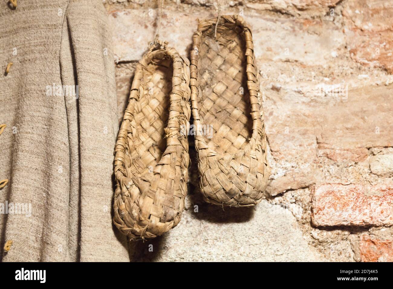 Vintage Russian bast shoes hang on brick wall. These shoes made from bast or fiber taken from the bark of trees such as linden or birch Stock Photo