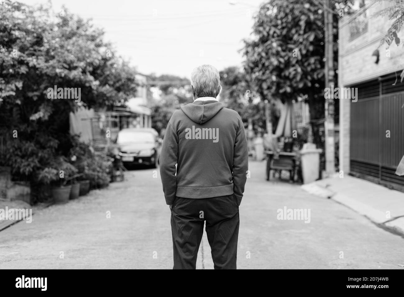 Back view of senior man standing while wearing jacket outdoors Stock Photo