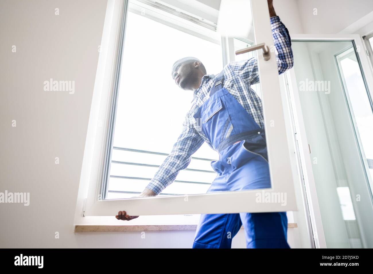 Young African Repairman In Overalls Installing Window Stock Photo