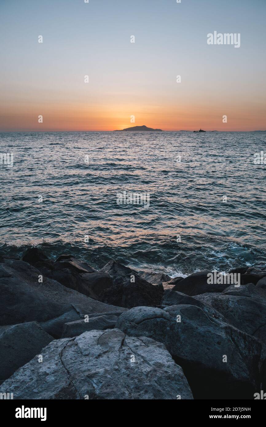 Sunset behing Ischia Island on the Sorrento Coast in Italy with Rocks and the Tyrrhenian Sea Coast Stock Photo