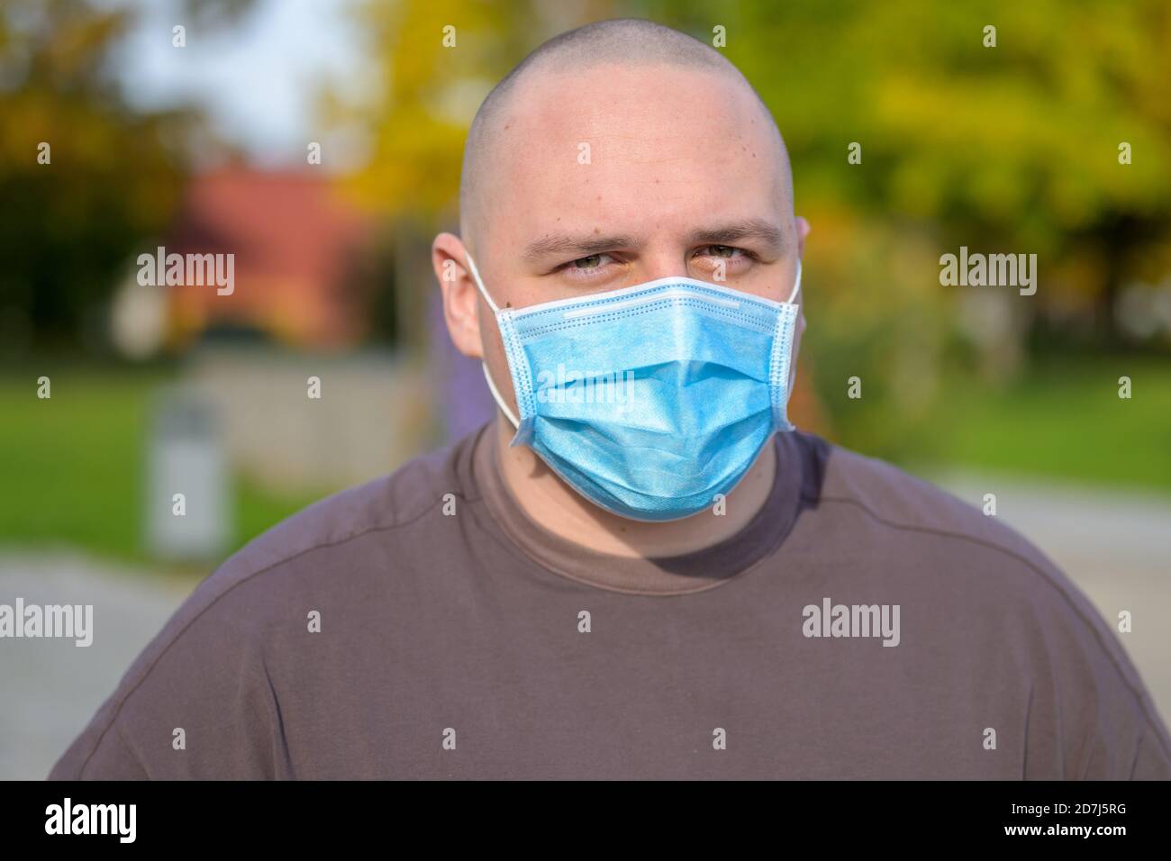 Young man wearing a face mask outdoors at home standing in his garden ...
