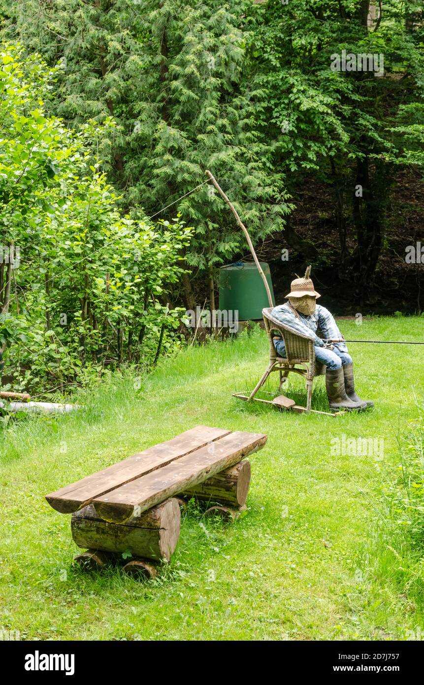 Scarecrow, made of hay, clothes and hat, funny human like figure, sitting  in a chair holding a fishing rod near a pond in Germany, Western Europe  Stock Photo - Alamy