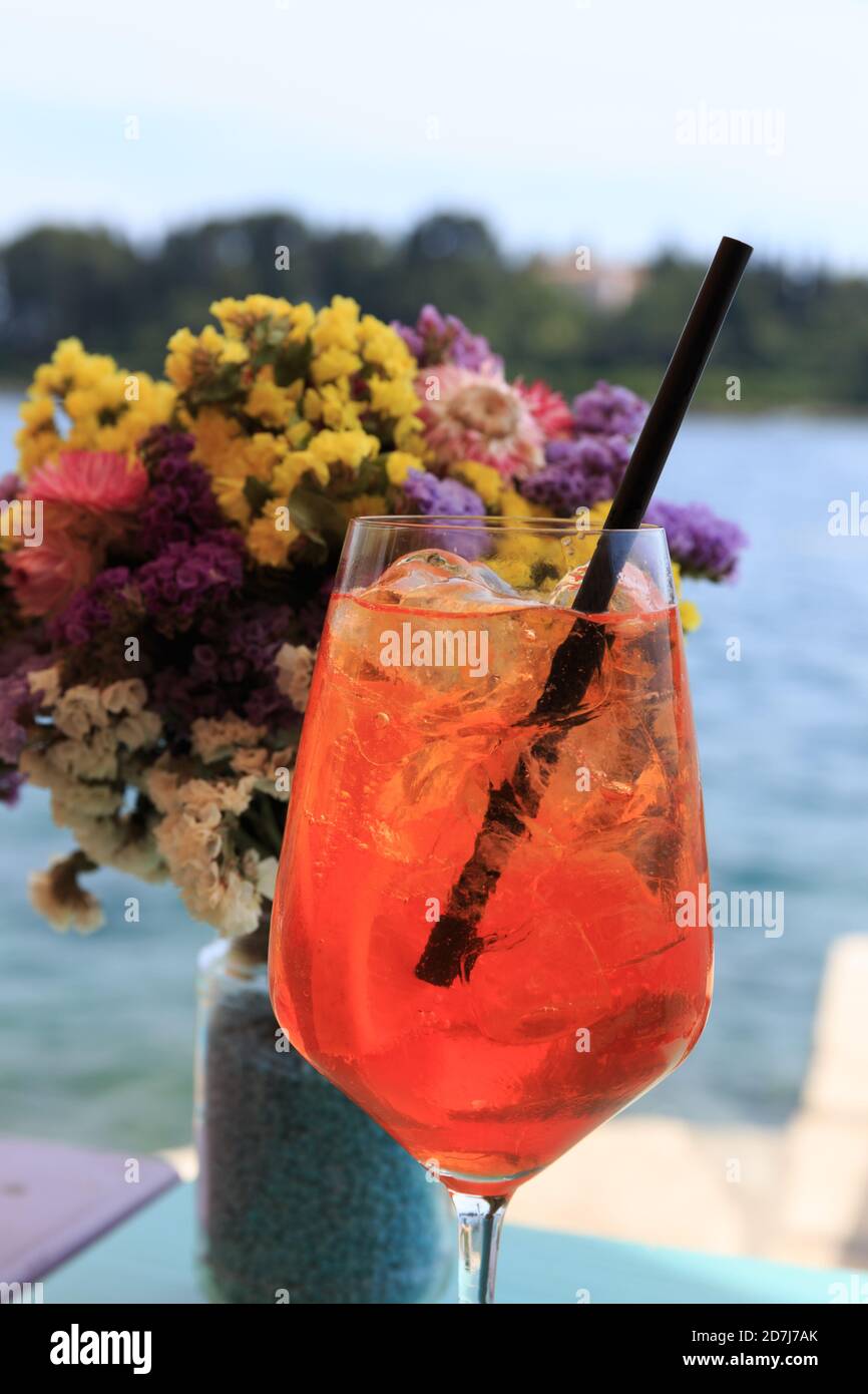 Close up of a cocktail with flowers and sea view on a sunny day, Rovinj, Croatia Stock Photo