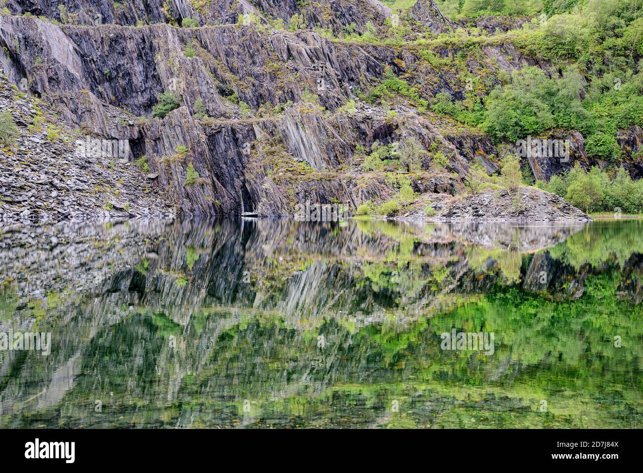 Slate cliffs reflecting in clear shiny lake in Scottish Highlands Stock Photo