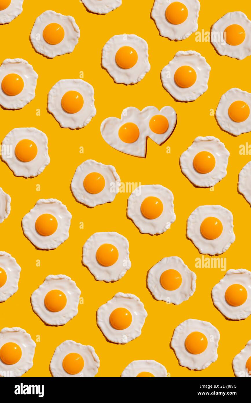 Pattern of fried eggs against yellow background Stock Photo