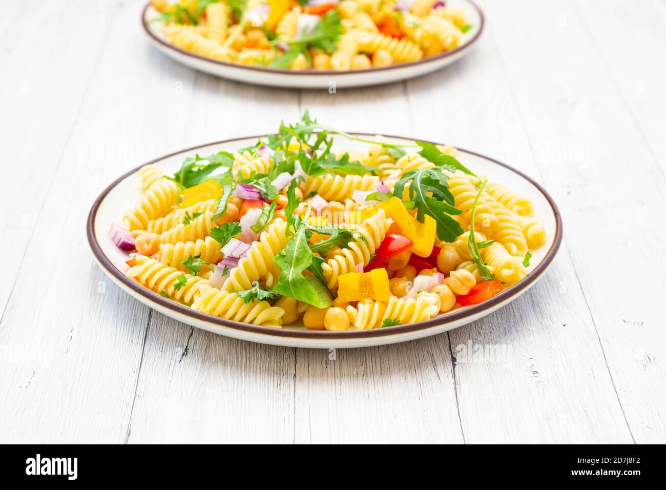 Plate of vegetarian pasta salad with chick-peas, bell pepper, arugula, onion, parsley and basil Stock Photo