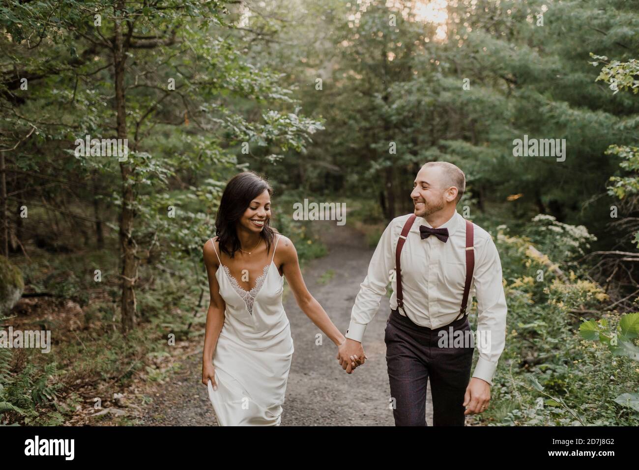 Couple holding hands while walking in forest Stock Photo - Alamy