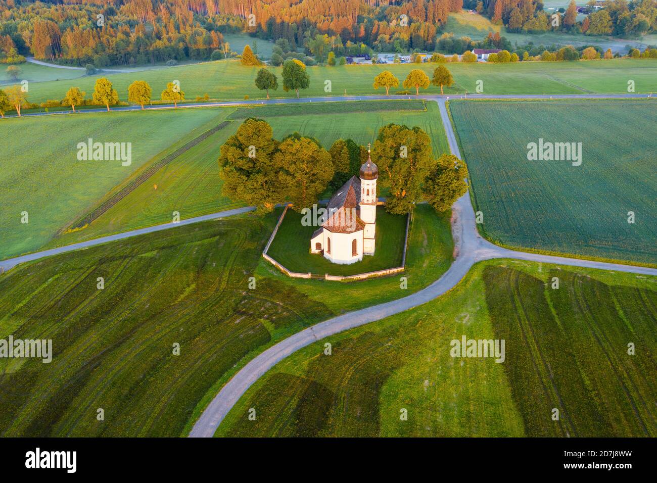 Germany, Bavaria, Etting, Drone view of Saint Andrew church surrounded by green fields at dawn Stock Photo