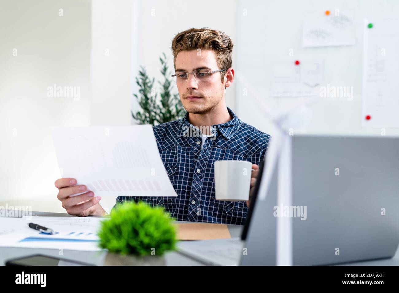 Man holding paper while drinking coffee at office Stock Photo