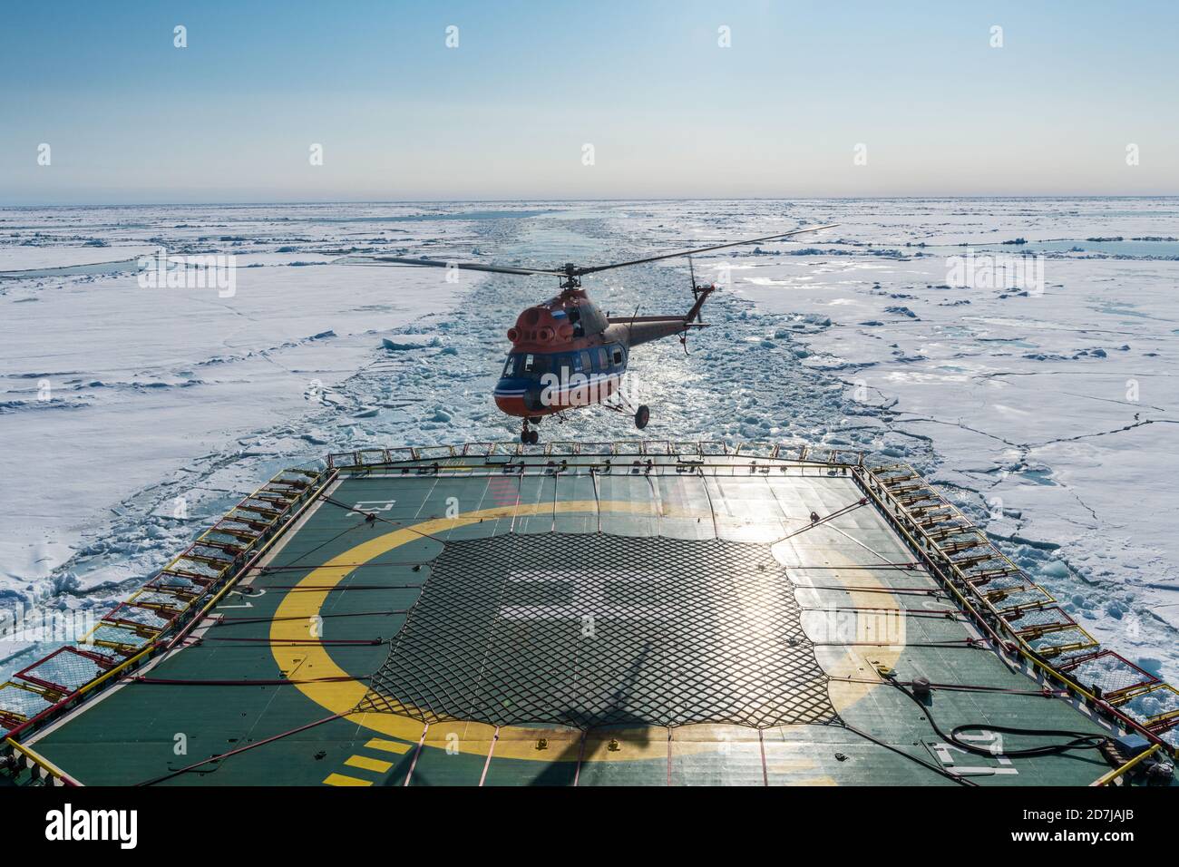 Helicopter landing on helipad of ice-breaker 50 Years of Victory cleaving through ice of Arctic Ocean Stock Photo