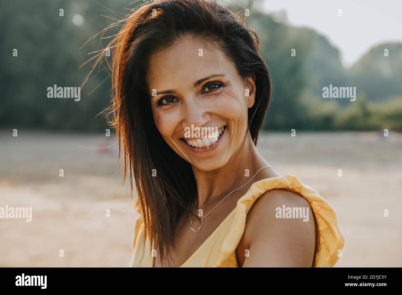 Smiling woman standing at beach on sunny day Stock Photo