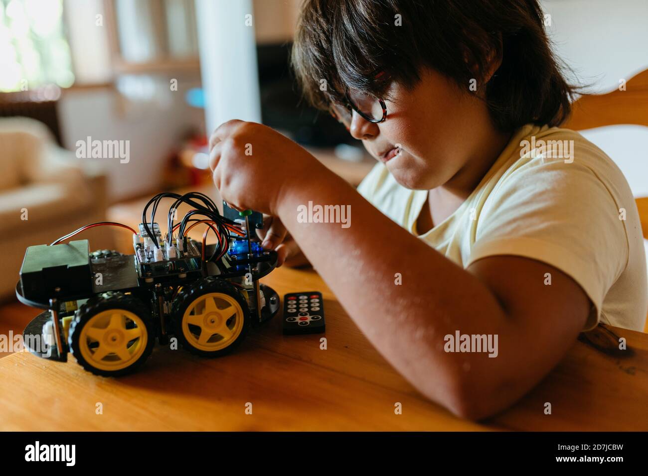 Boy repairing remote controlled car while sitting by table at home Stock Photo