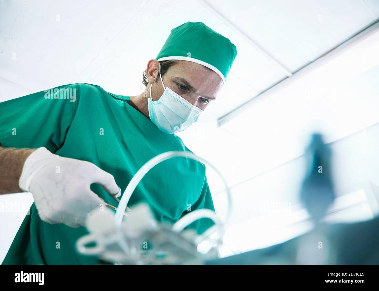 Male surgeon operating in illuminated intensive care unit at hospital Stock Photo