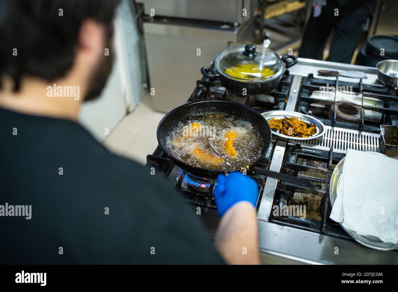 Chef frying food in cooking pan while standing at kitchen counter Stock