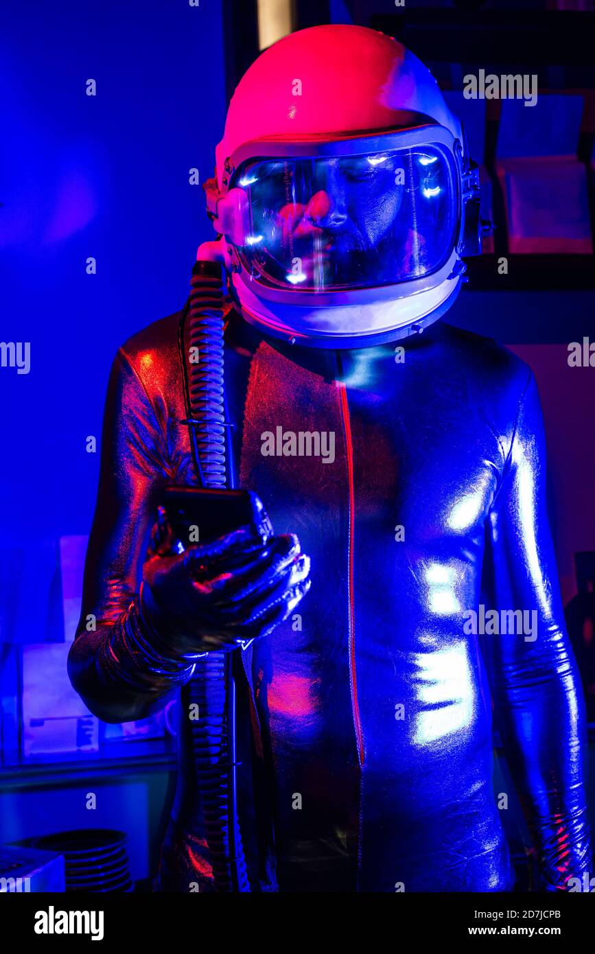 Male astronaut wearing space suit using smart phone while standing in ...