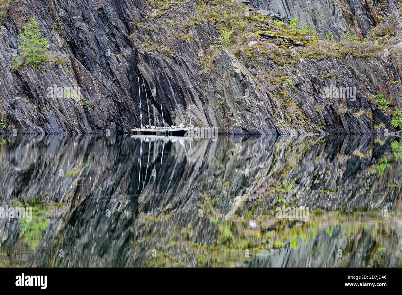 Slate cliffs reflecting in clear shiny lake in Scottish Highlands Stock Photo