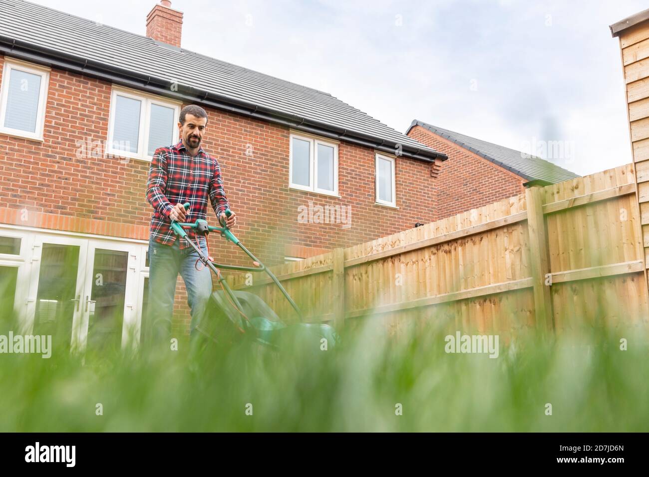 Man mowing lawn with lawn mower at backyard Stock Photo