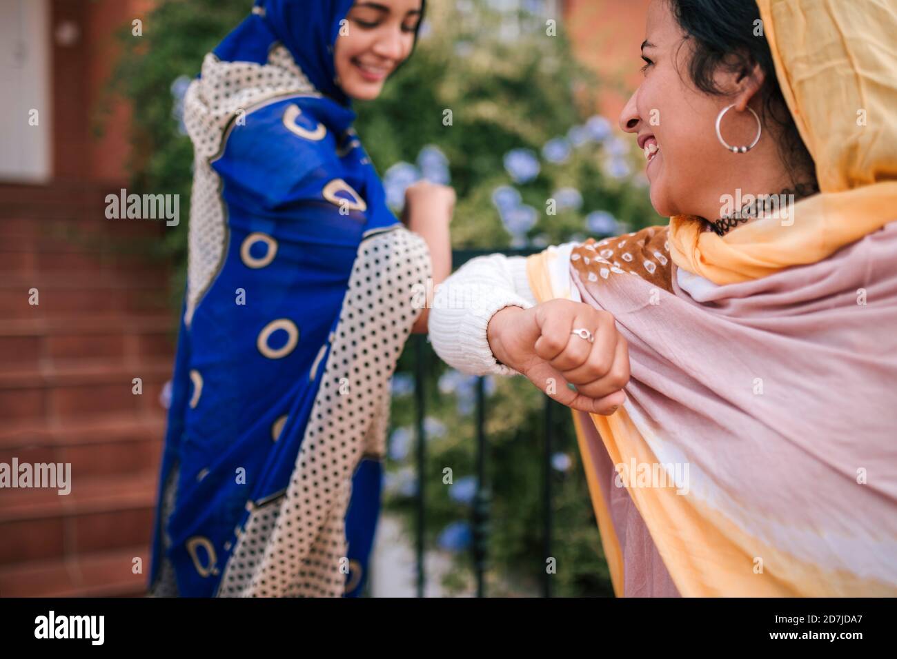 Smiling friends doing elbow bump while standing outdoors Stock Photo