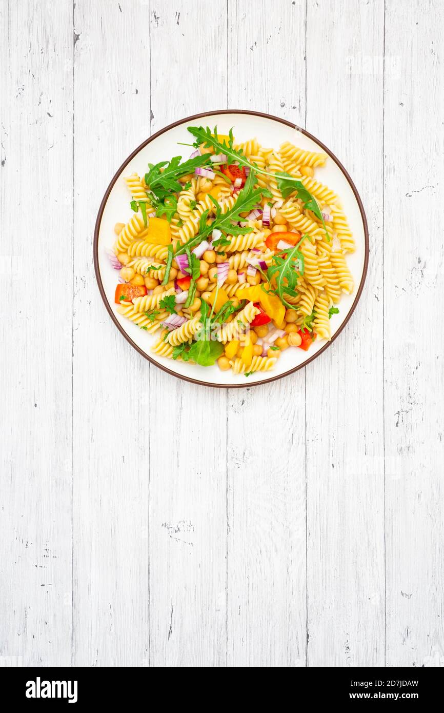 Plate of vegetarian pasta salad with chick-peas, bell pepper, arugula, onion, parsley and basil Stock Photo