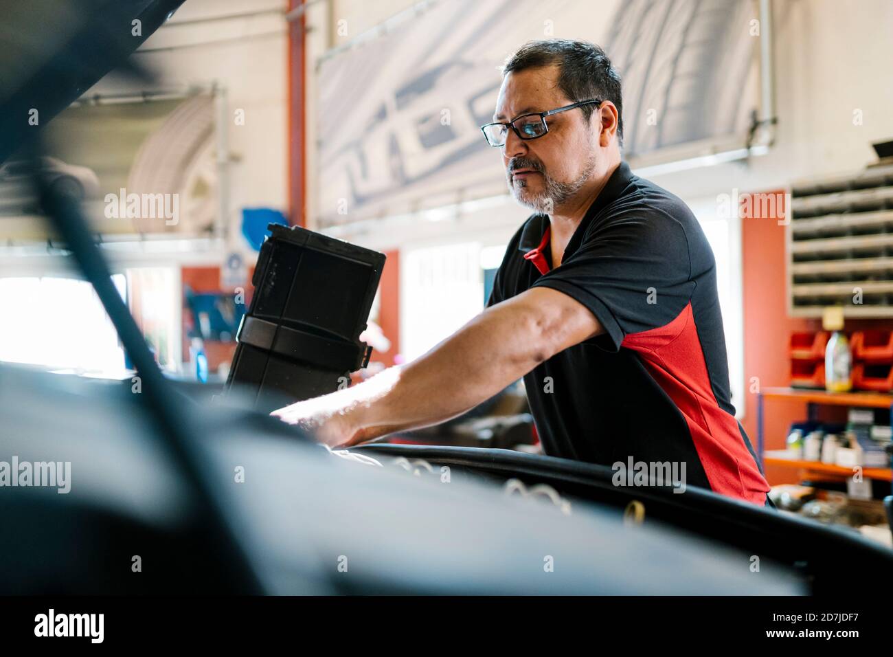 Male mechanic repairing car while standing in garage Stock Photo - Alamy