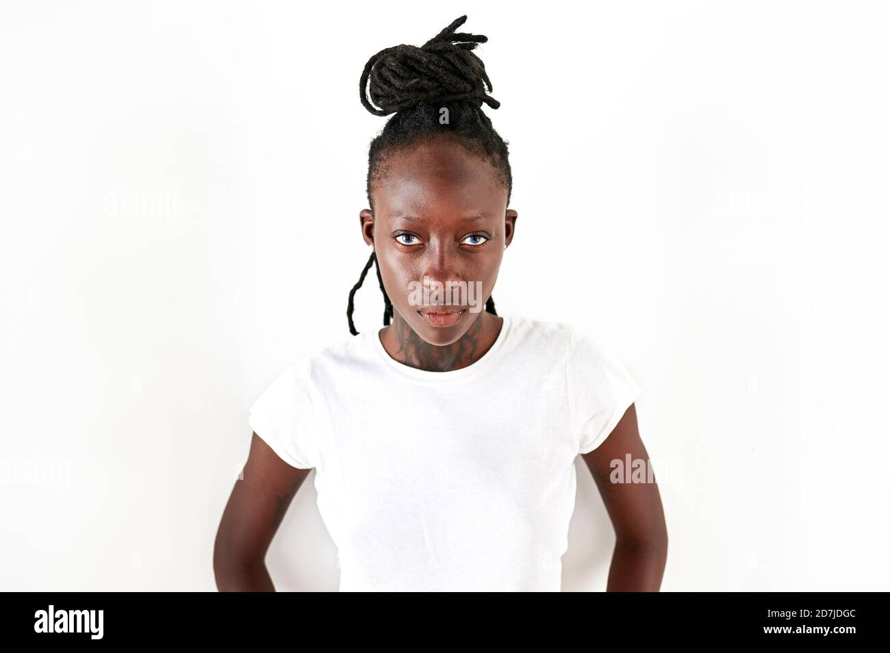 Serious young woman with locs standing against white background Stock Photo