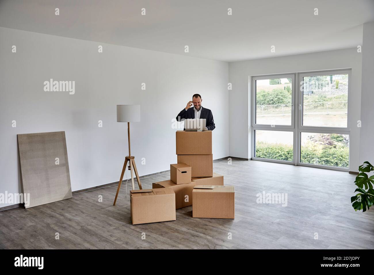 Mature man using laptop while standing in new house Stock Photo