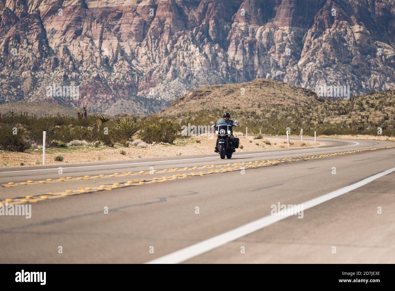 Man riding motorcycle on highway against mountain hires stock