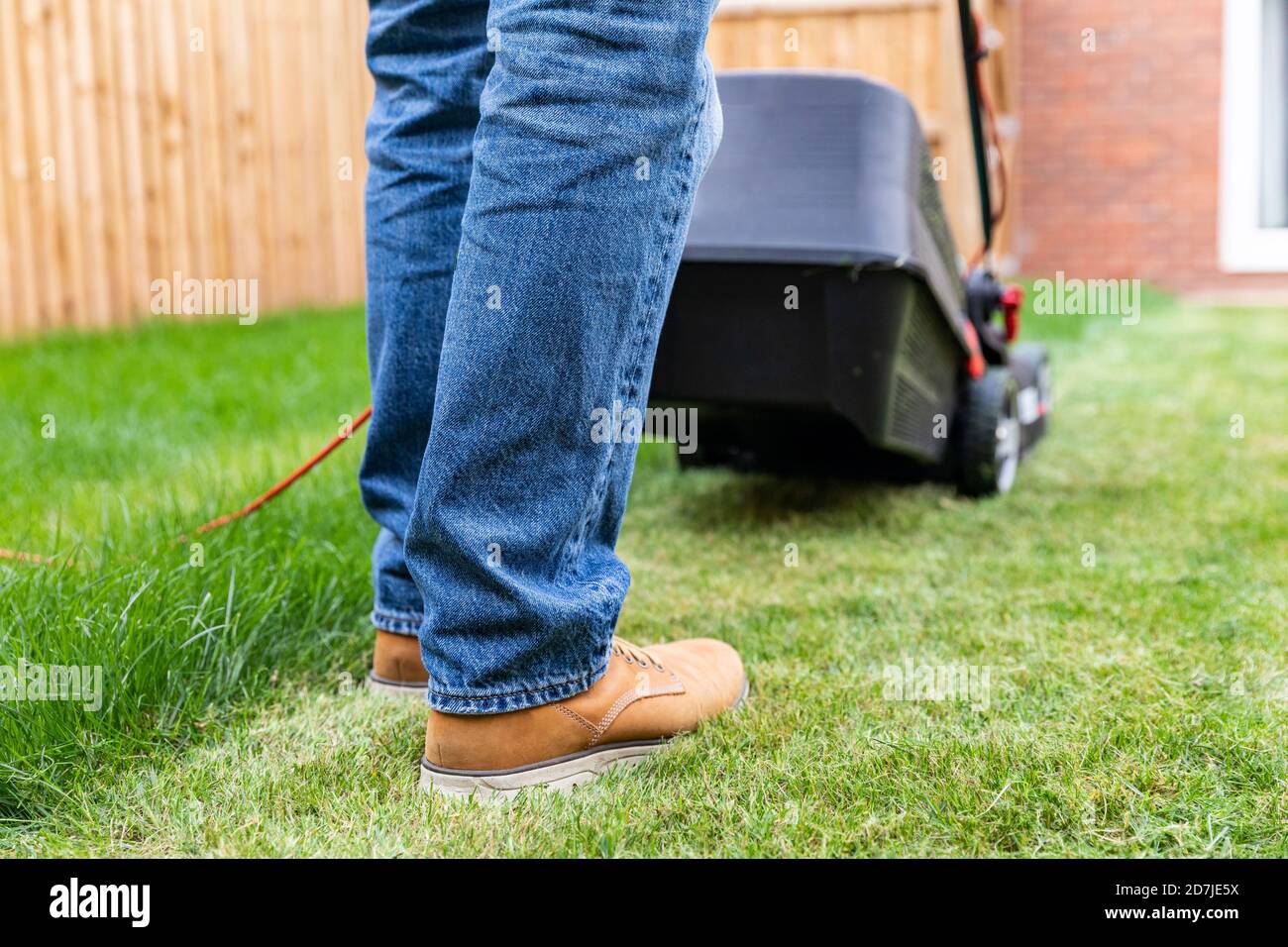 Man standing with lawn mower at backyard Stock Photo