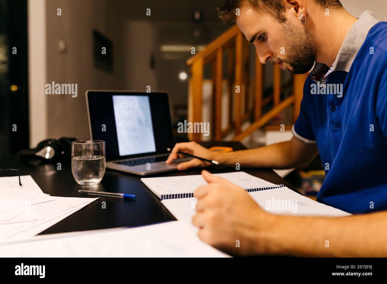 Young man focused on doing homework while sitting with laptop at home Stock Photo
