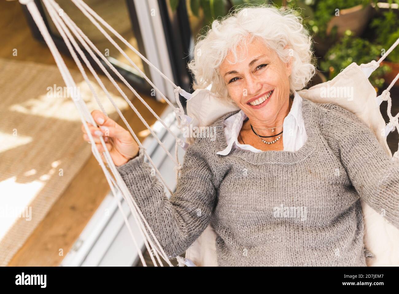 Smiling mature woman sitting on swing at home Stock Photo - Alamy
