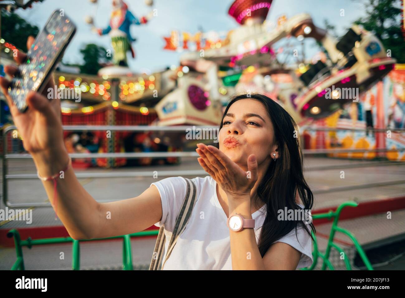 Young woman blowing kiss while taking selfie at amusement park Stock Photo