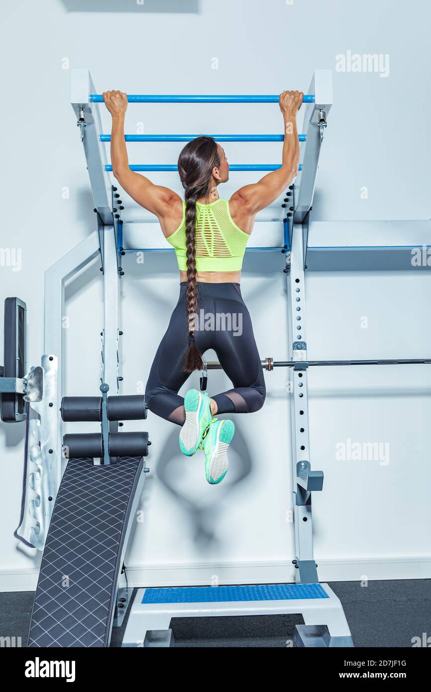 Female athlete exercising on chin-ups bars in gym Stock Photo