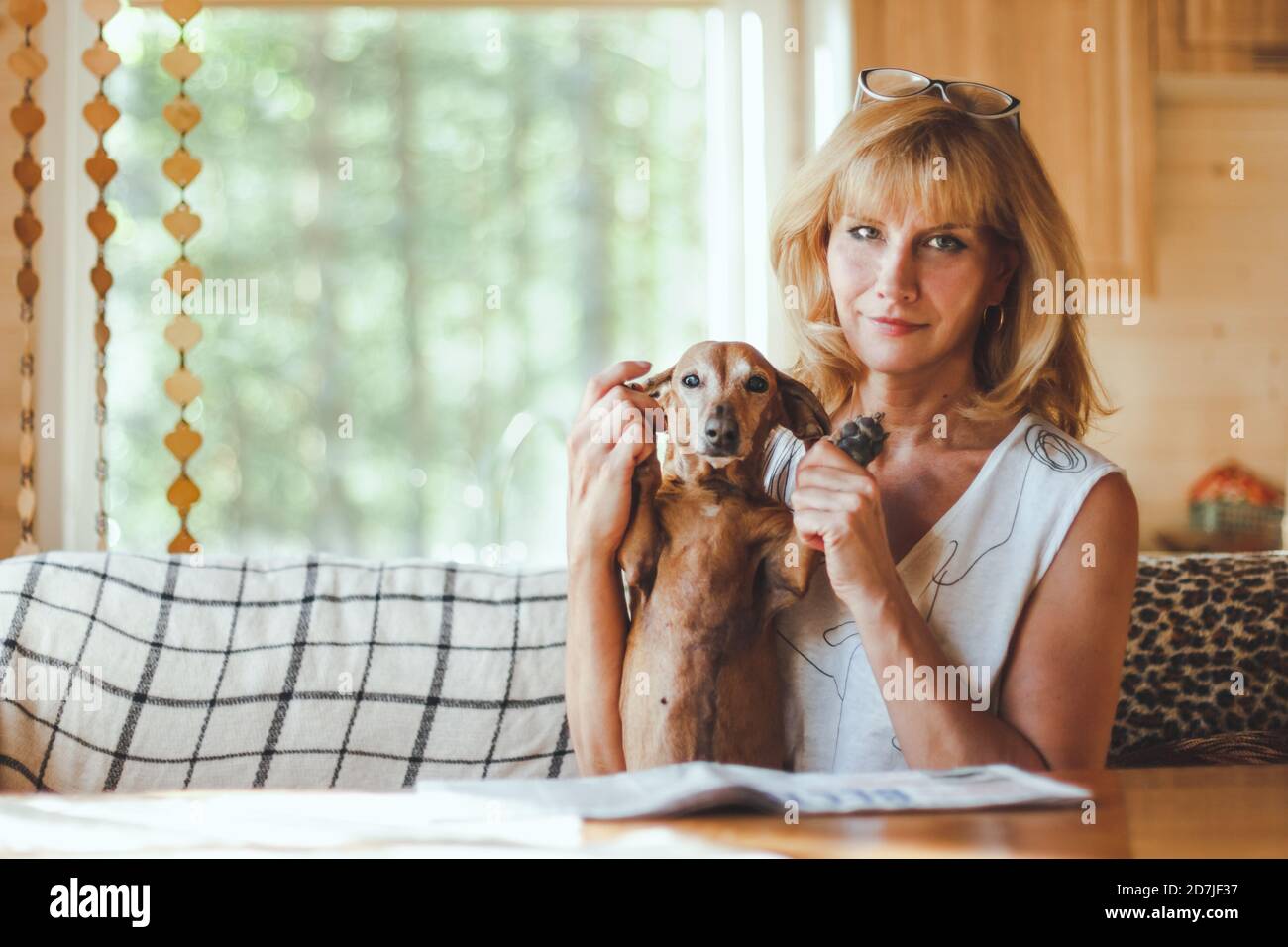 Adult woman sitting in a cozy kitchen with her dachshund dog Stock Photo