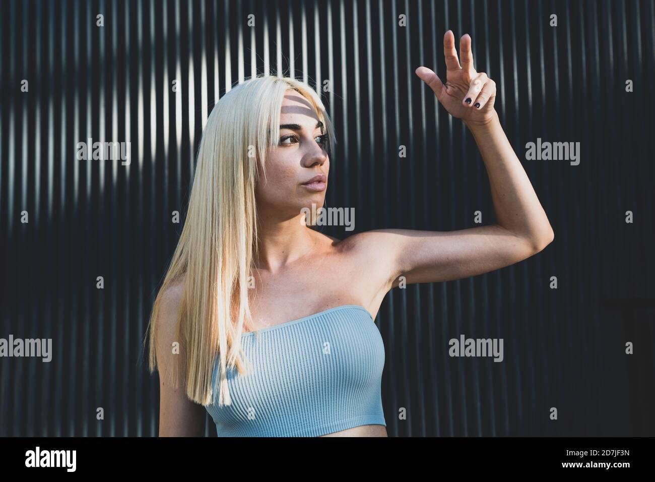 Young woman wearing off shoulder top gesturing while standing against wall Stock Photo