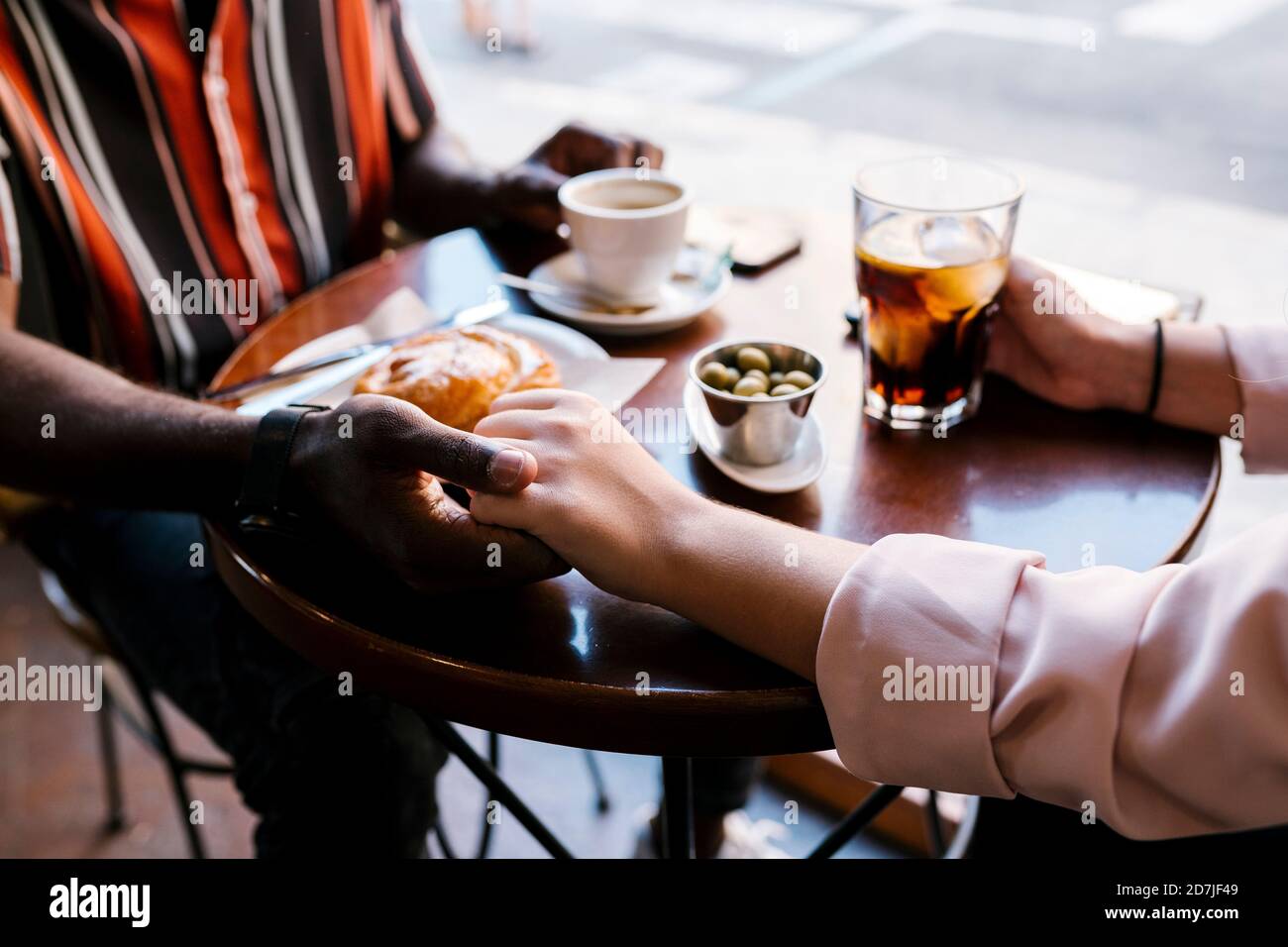 Romantic young couple holding hands while having drinks in coffee shop Stock Photo