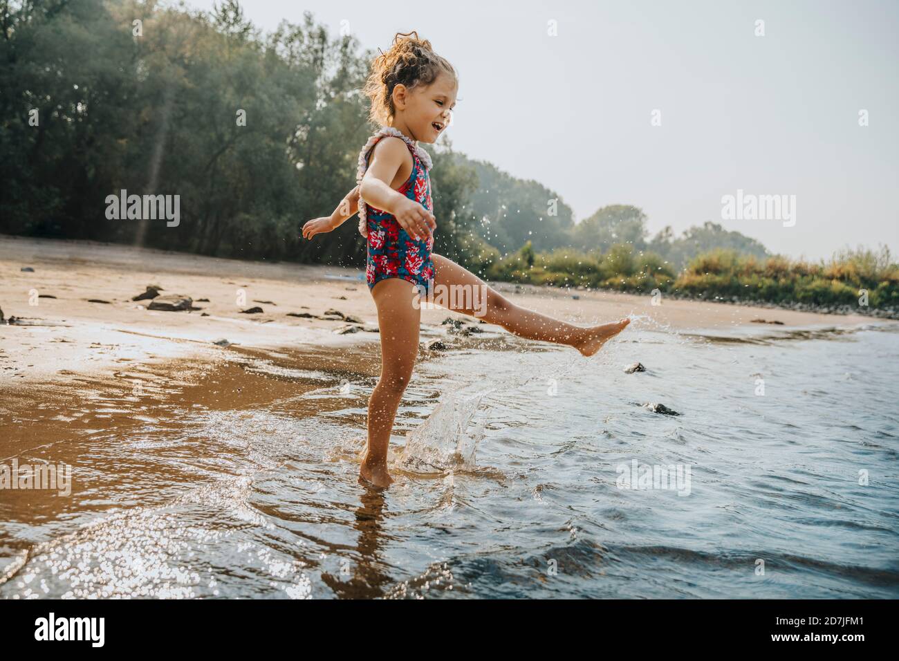 Cute little girl playing in water at beach on sunny day Stock ...