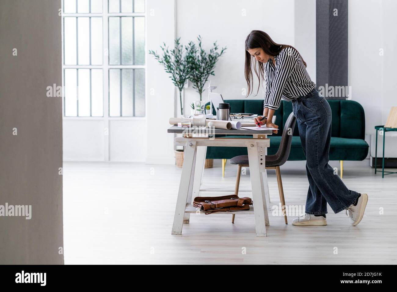 Young female architect leaning on desk while working at creative office Stock Photo