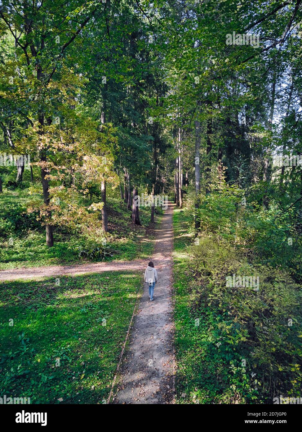 Woman walking on footpath amidst trees in park Stock Photo
