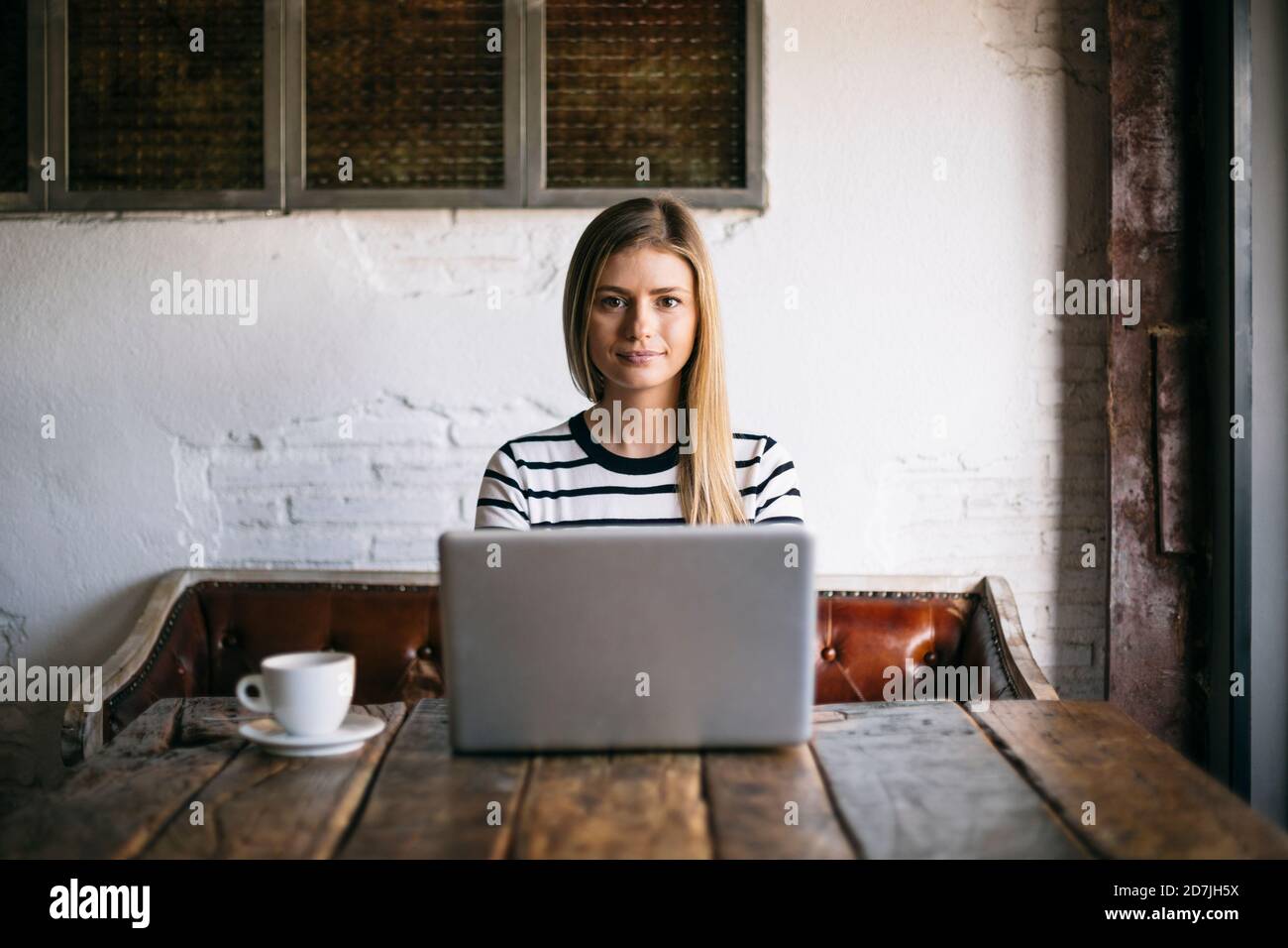 Woman using laptop while sitting in cafe Stock Photo