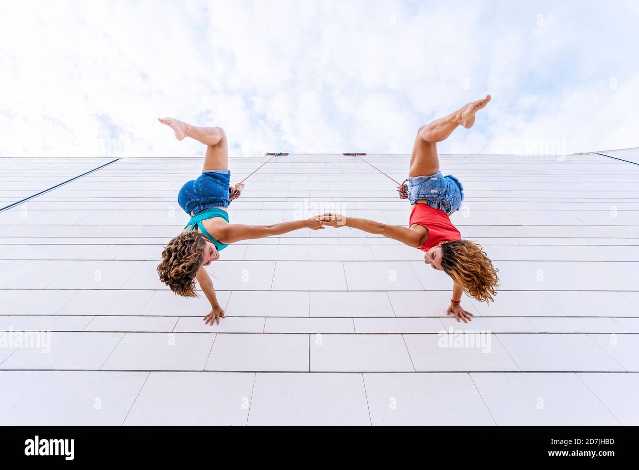 Aerial dancers upside down holding hands while hanging on window Stock Photo