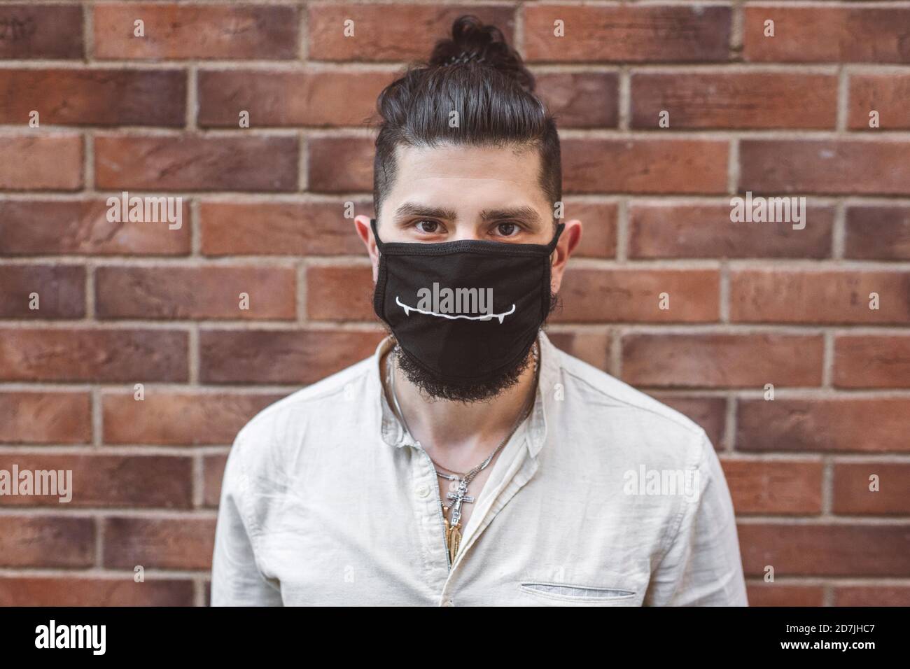 Man wearing face mask against brick wall during coronavirus crisis Stock Photo